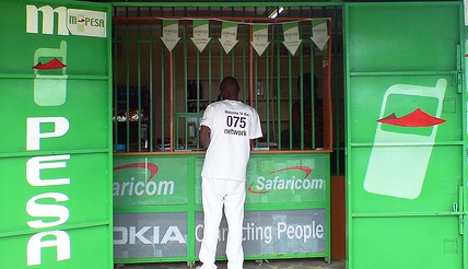 M-Pesa agent in Kisumu processing mobile money transactions for customers at Kondele interchange